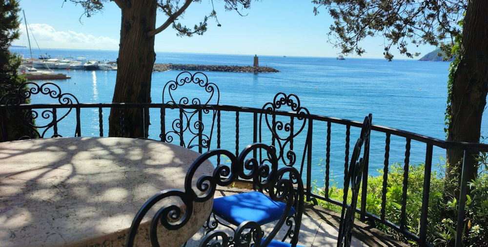 An iron table and chairs on a balcony over the sea