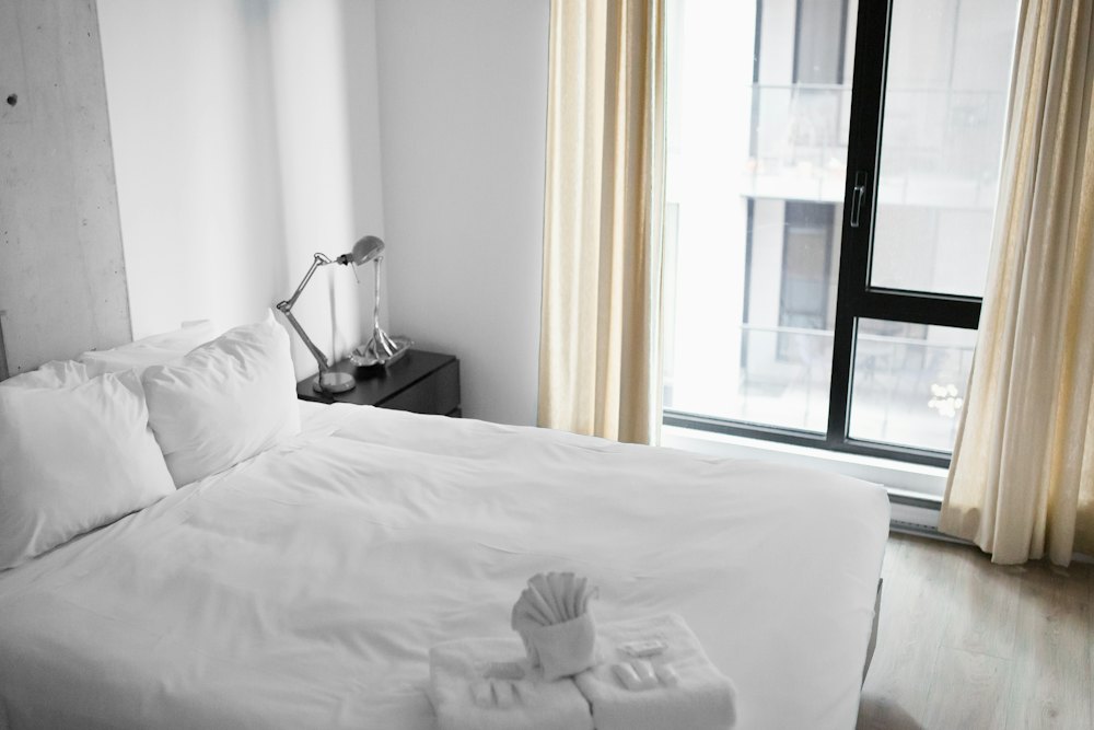 A bright room with a white bed beside a tall window