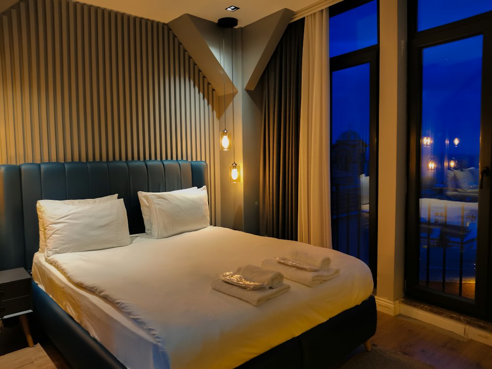 A double bed with towels laid out, wood-panelled walls and evening light