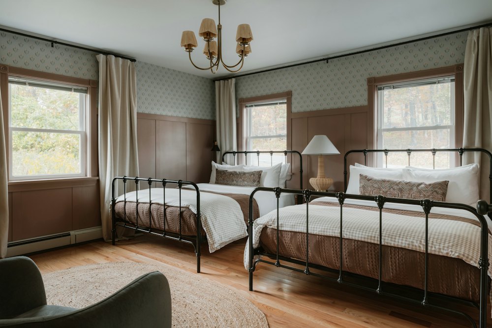 Two iron-framed single beds in a room with three windows