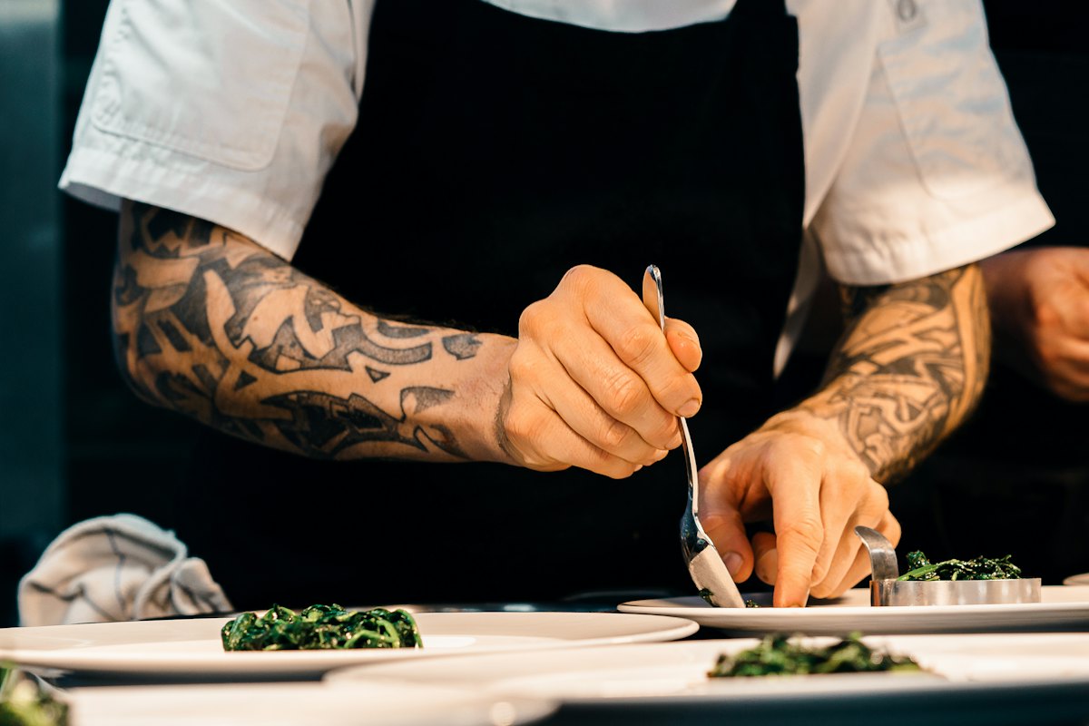 A cook plating a dish at the pass