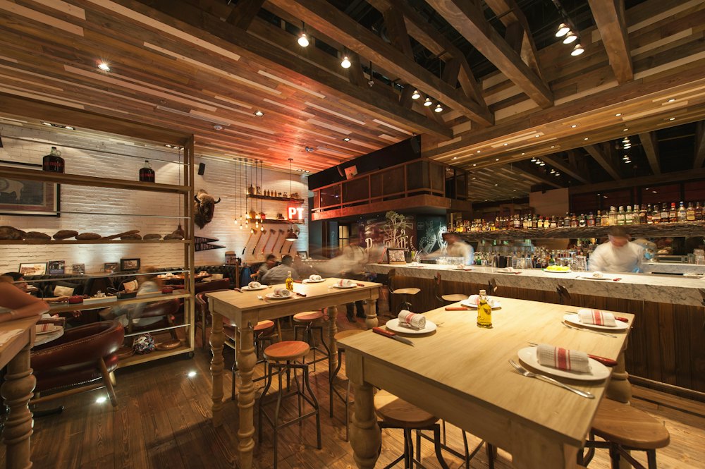The dining room with wooden tables and an open kitchen