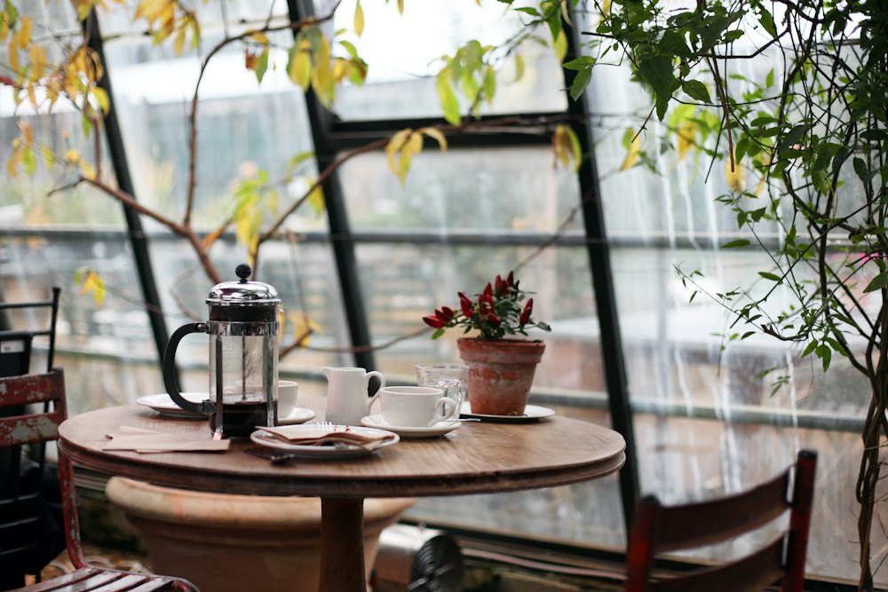 A window table set with a French press and cups