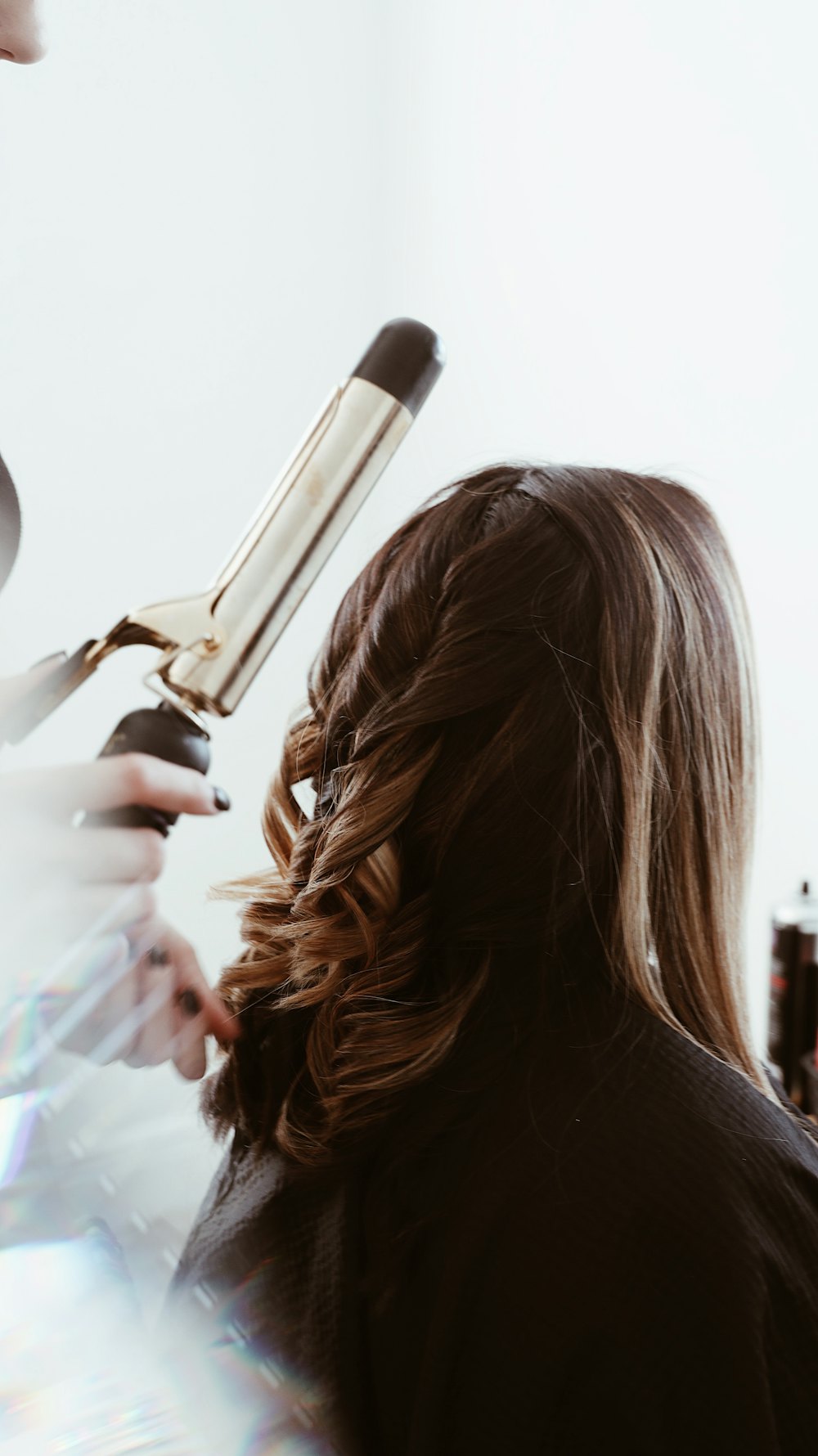 Brown hair being curled with a tong
